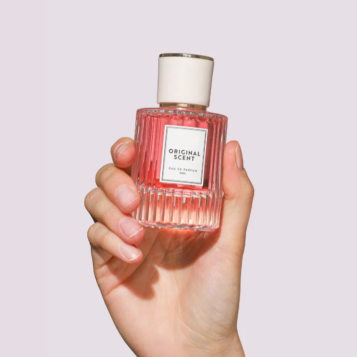 Hand holding a vibrant red bottle of Original Scent Eau de Parfum, 30ml